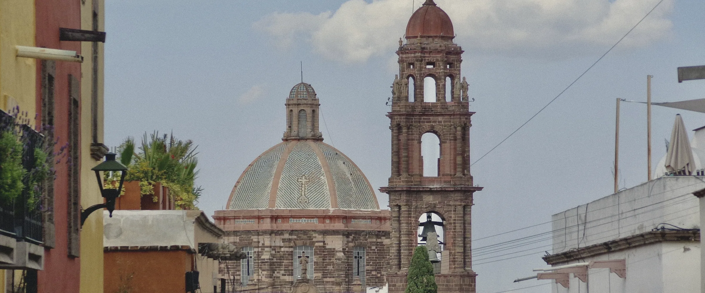 A street of colourful colonial buildings leading to a domed church in San Miguel de Allende.